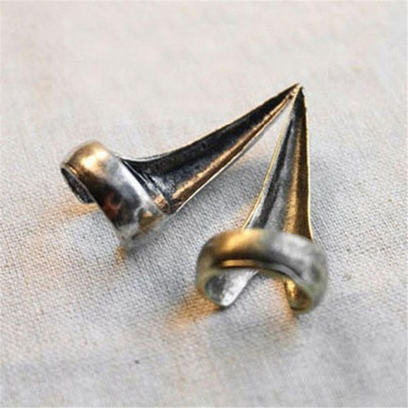 Close-up of two dramatic claw-shaped rings in silver and gold, showcasing retro punk gothic style for bold statement fashion.