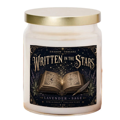 A 9 oz glass jar candle with a gold lid and a dark navy label reading 'Written in the Stars' and 'Lavender & Sage' by Shadow Threadz, styled on a wooden cutting board with a plaid cloth and small pumpkins in the background.