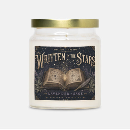 A glass jar candle with a gold metal lid and a dark illustrated label reading 'Written in the Stars' and 'Lavender + Sage' from The Enchanted Collection, centered on a light gray background.